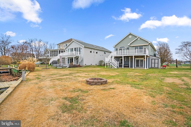 rear view of house featuring a fire pit, a lawn, and a wooden deck