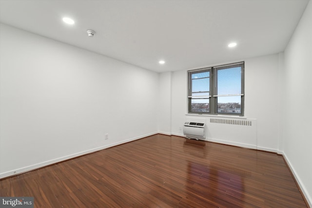 spare room featuring heating unit and dark wood-type flooring