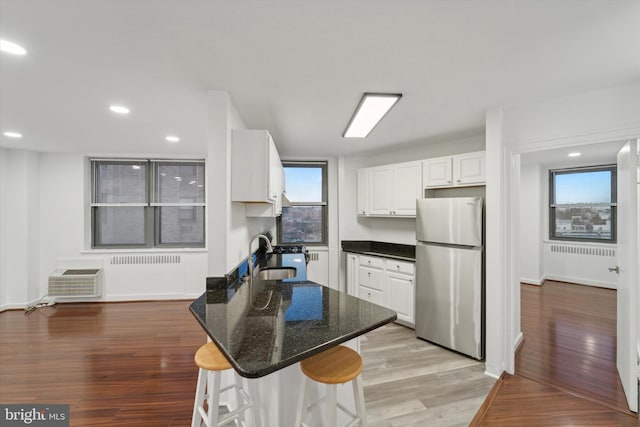 kitchen with stainless steel refrigerator, white cabinetry, sink, light hardwood / wood-style flooring, and plenty of natural light