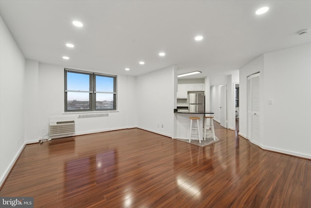 unfurnished living room featuring dark hardwood / wood-style floors and an AC wall unit