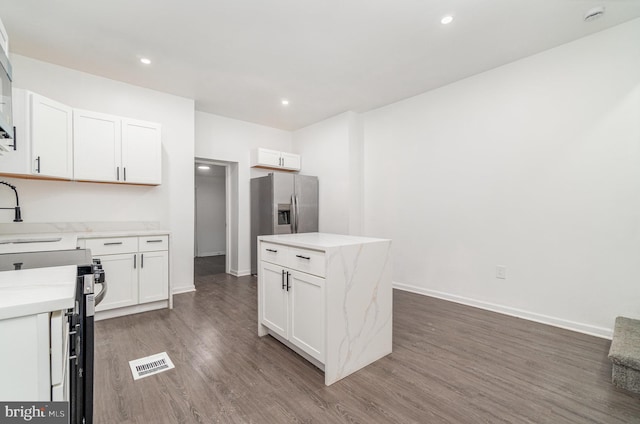 kitchen with a center island, white cabinets, stainless steel fridge, dark hardwood / wood-style flooring, and range