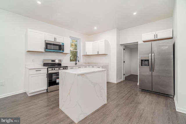 kitchen with white cabinets, appliances with stainless steel finishes, light wood-type flooring, and a kitchen island