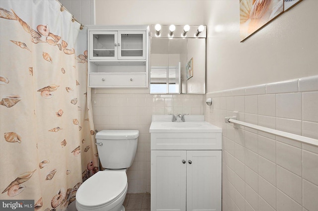 bathroom featuring vanity, tile walls, and toilet