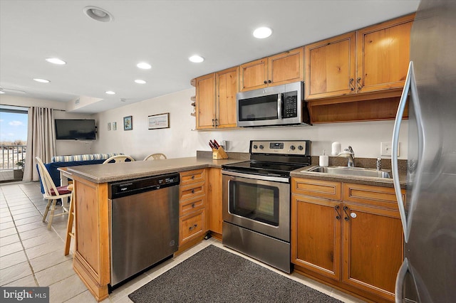 kitchen with light tile patterned flooring, kitchen peninsula, sink, and appliances with stainless steel finishes