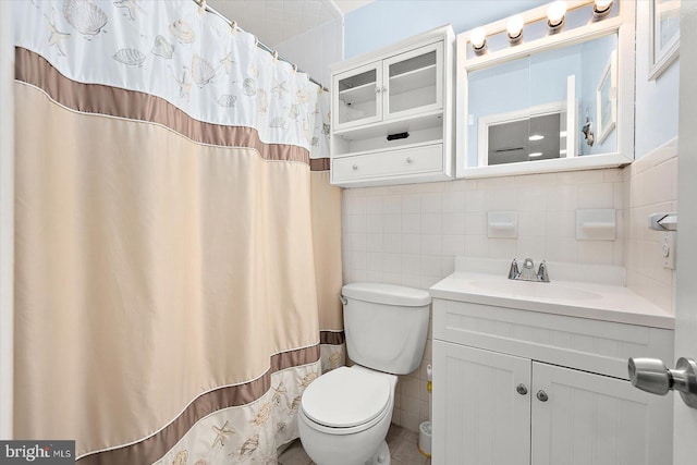 bathroom featuring a shower with shower curtain, vanity, toilet, and tile walls