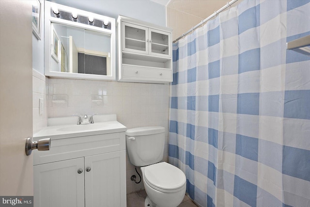 bathroom featuring vanity, tile walls, and toilet