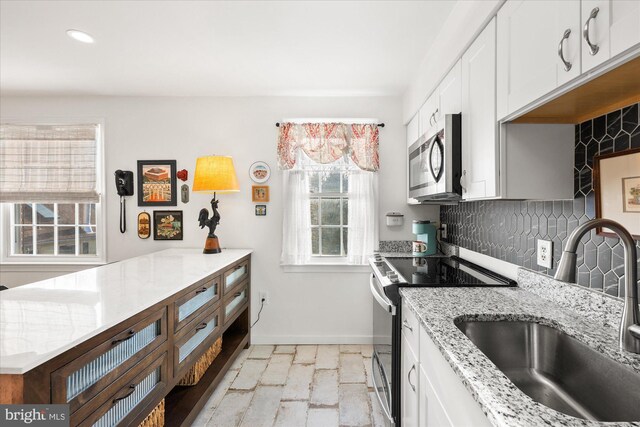 kitchen featuring decorative backsplash, stainless steel appliances, white cabinetry, and sink