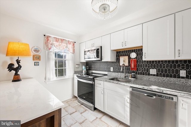 kitchen featuring sink, light stone countertops, appliances with stainless steel finishes, tasteful backsplash, and white cabinetry