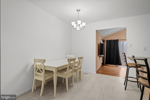 dining area featuring light hardwood / wood-style floors, lofted ceiling, and an inviting chandelier