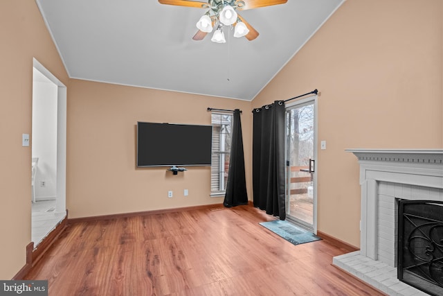 unfurnished living room with ceiling fan, a fireplace, vaulted ceiling, and light wood-type flooring