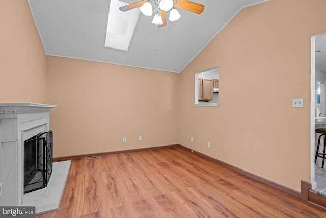 unfurnished living room with ceiling fan, light wood-type flooring, and lofted ceiling with skylight