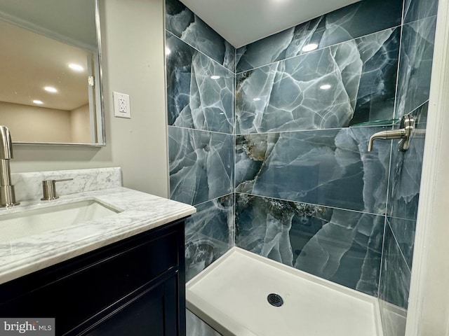 bathroom with tiled shower and vanity