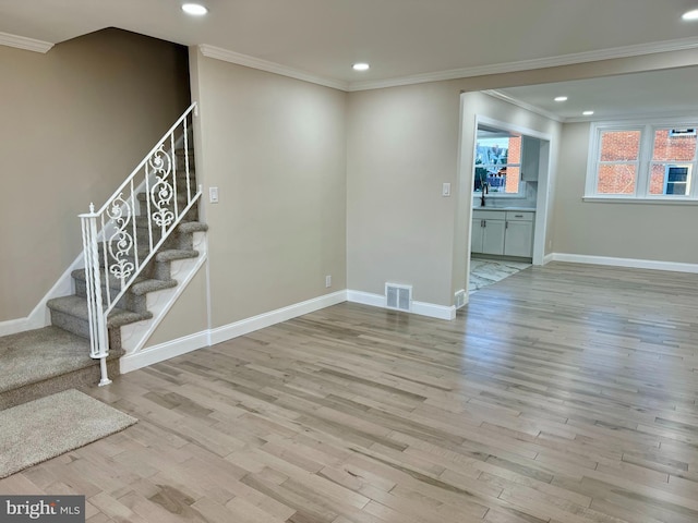 basement featuring sink, crown molding, and light hardwood / wood-style flooring