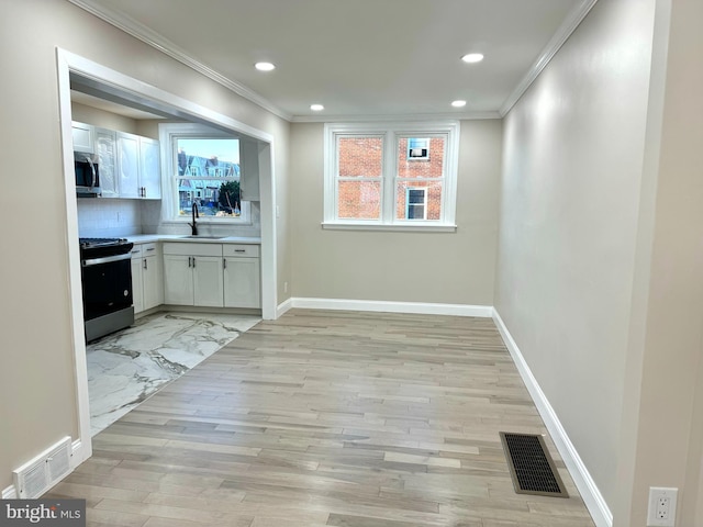 interior space with white cabinetry, sink, black / electric stove, decorative backsplash, and ornamental molding