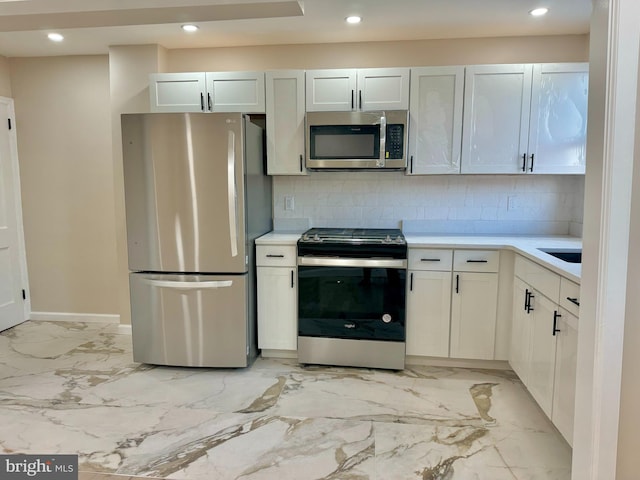 kitchen featuring decorative backsplash, white cabinetry, and appliances with stainless steel finishes