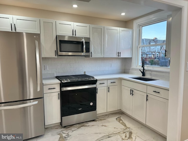 kitchen with appliances with stainless steel finishes, tasteful backsplash, white cabinetry, and sink