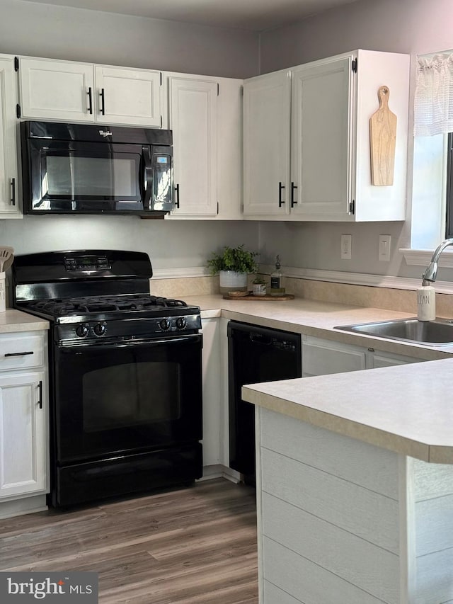 kitchen featuring white cabinets, wood-type flooring, sink, and black appliances