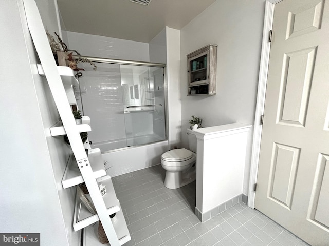 bathroom featuring combined bath / shower with glass door, tile patterned flooring, and toilet