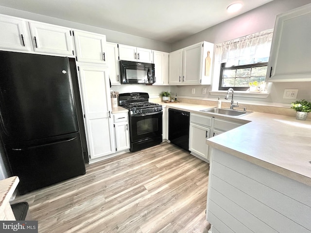 kitchen with sink, light hardwood / wood-style flooring, white cabinetry, and black appliances