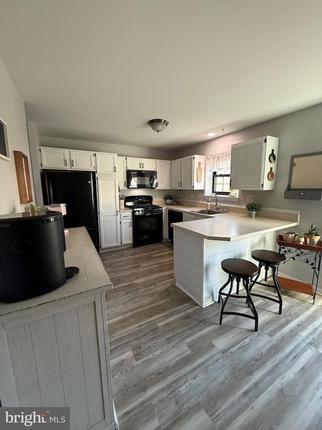 kitchen featuring white cabinets, sink, light hardwood / wood-style flooring, and black appliances