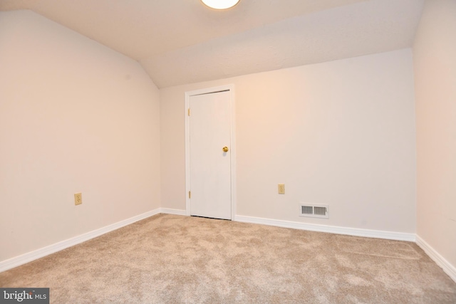 empty room with light colored carpet and vaulted ceiling