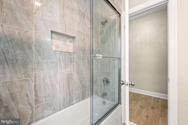 bathroom with hardwood / wood-style floors and combined bath / shower with glass door