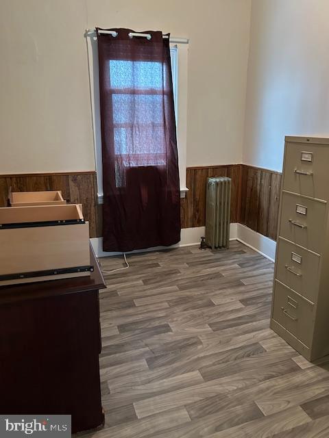 interior space with hardwood / wood-style flooring, radiator, and wooden walls