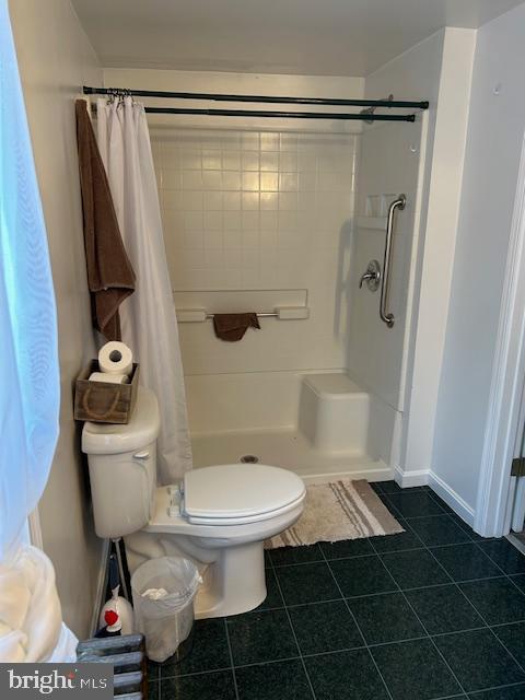 bathroom with tile patterned floors, walk in shower, and toilet