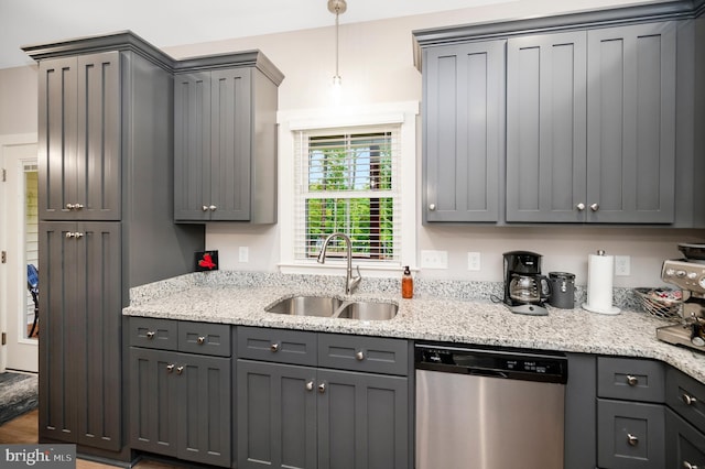 kitchen with stainless steel dishwasher, sink, pendant lighting, hardwood / wood-style flooring, and gray cabinets