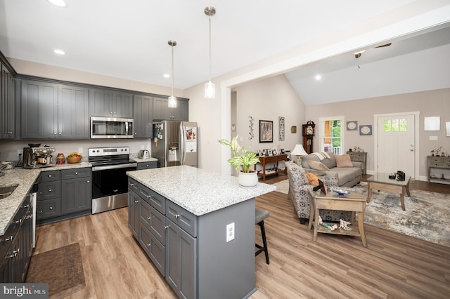 kitchen with gray cabinetry, light hardwood / wood-style flooring, decorative light fixtures, a kitchen island, and appliances with stainless steel finishes