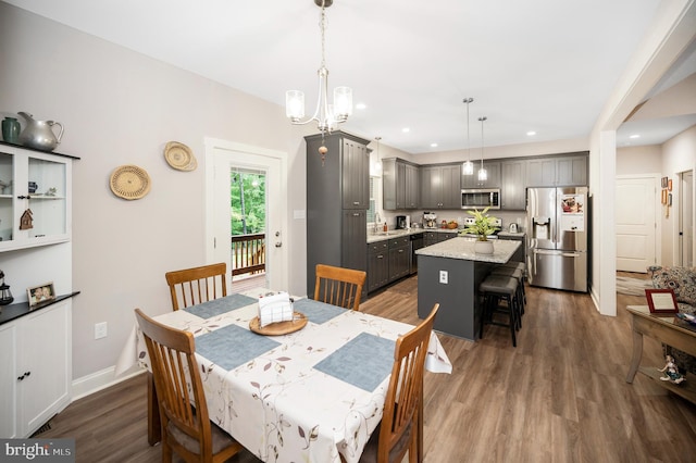 dining space featuring sink, dark wood-type flooring, and a notable chandelier