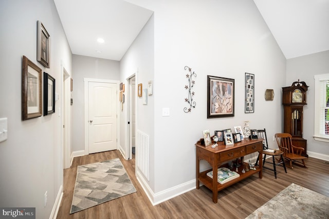 corridor featuring wood-type flooring and vaulted ceiling