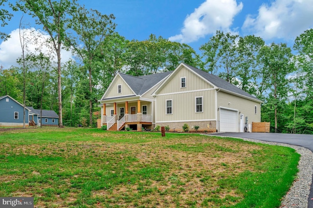 view of front facade with covered porch, a garage, and a front yard