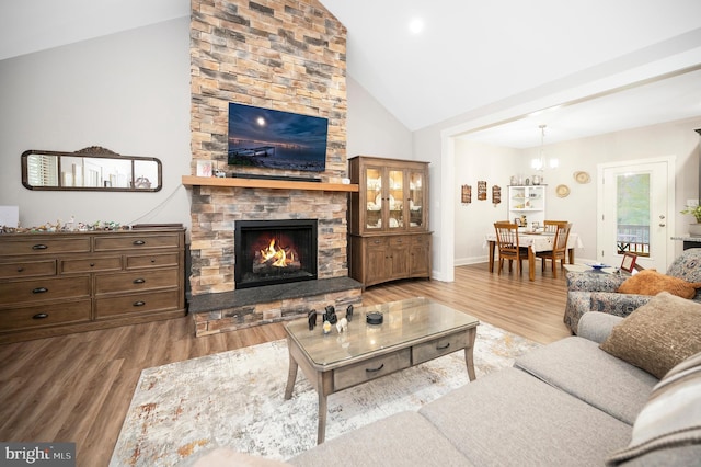 living room featuring a fireplace, wood-type flooring, a chandelier, and high vaulted ceiling