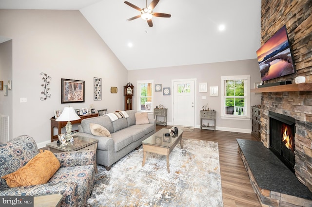 living room featuring a stone fireplace, hardwood / wood-style floors, high vaulted ceiling, and a healthy amount of sunlight