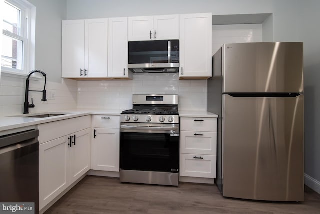 kitchen featuring white cabinets, appliances with stainless steel finishes, dark hardwood / wood-style flooring, and sink