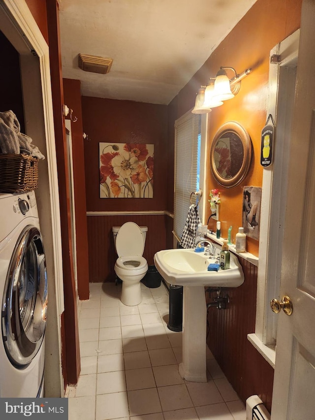 bathroom featuring toilet, tile patterned floors, a baseboard heating unit, and washer / clothes dryer