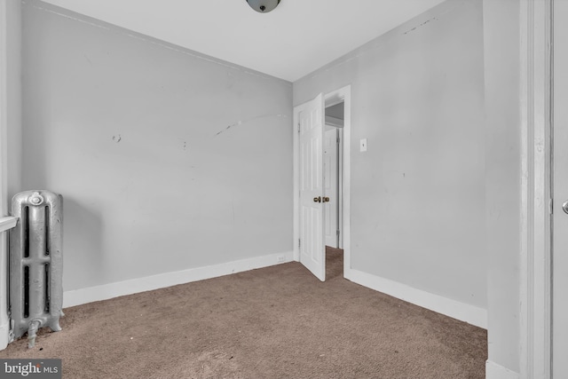 carpeted empty room featuring radiator heating unit