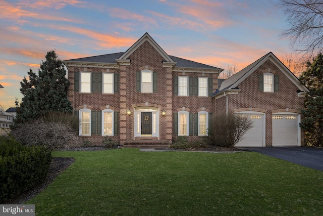 colonial inspired home featuring a garage and a yard