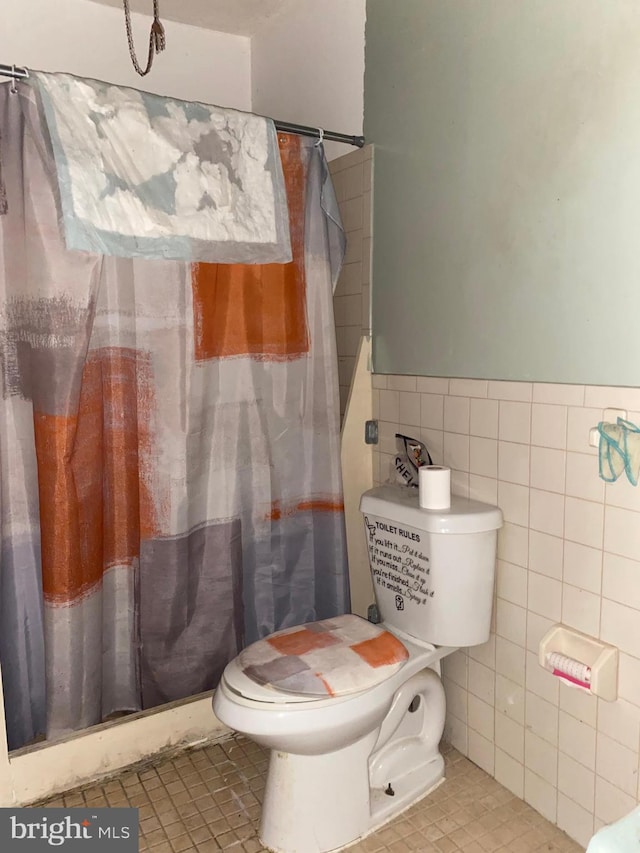 bathroom with tile patterned floors, toilet, and tile walls