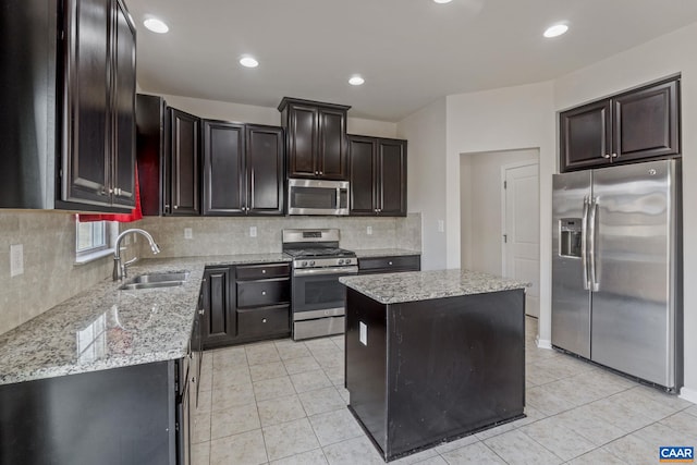 kitchen featuring sink, a center island, tasteful backsplash, light stone counters, and appliances with stainless steel finishes