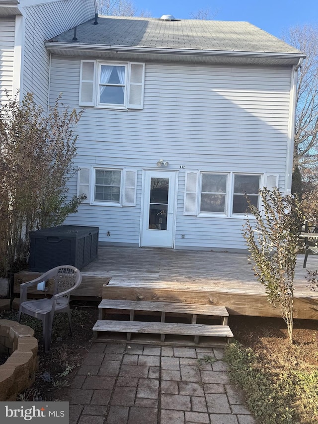 back of property with a deck and a hot tub