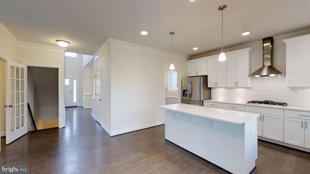 kitchen with white cabinetry, wall chimney exhaust hood, stainless steel appliances, and a center island