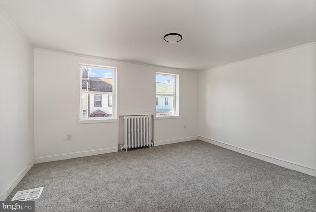 carpeted spare room with radiator and crown molding