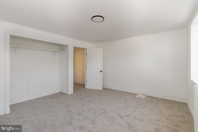 unfurnished bedroom featuring light carpet, a closet, and ornamental molding