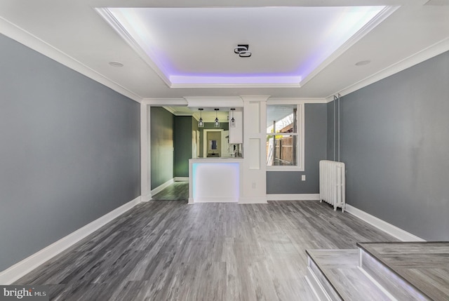 interior space with hardwood / wood-style flooring, radiator heating unit, crown molding, and a tray ceiling