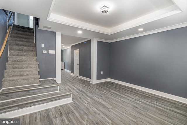 interior space featuring dark hardwood / wood-style flooring, a raised ceiling, and ornamental molding