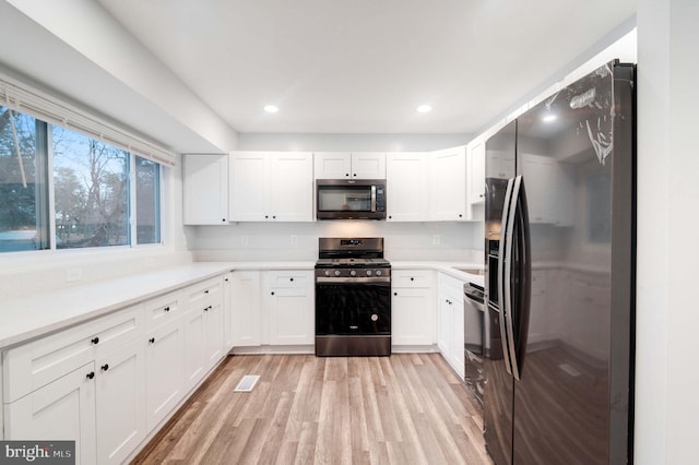 kitchen featuring white cabinetry, light hardwood / wood-style floors, and appliances with stainless steel finishes