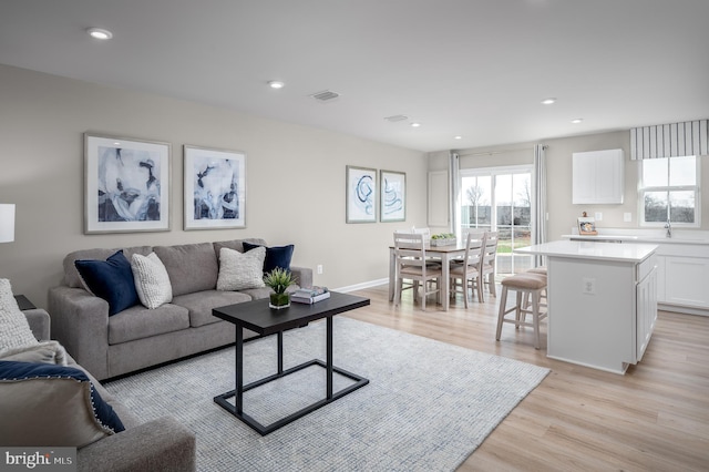 living room with light hardwood / wood-style floors and sink