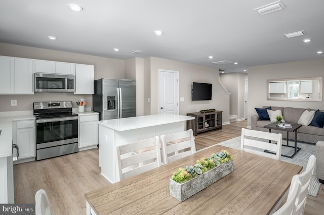 kitchen featuring stainless steel appliances, white cabinetry, a kitchen island, and light hardwood / wood-style flooring